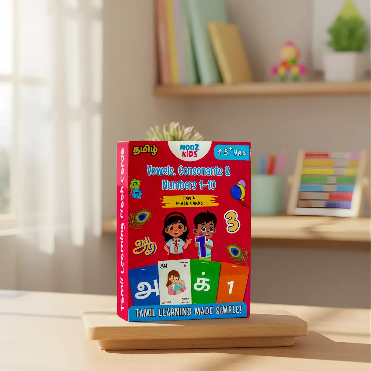 Tamil learning flash cards packaging on a wooden stand with a blurred classroom background